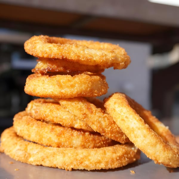 A stack of golden-brown, crispy onion rings from Burger MOOvment, ready to be enjoyed.